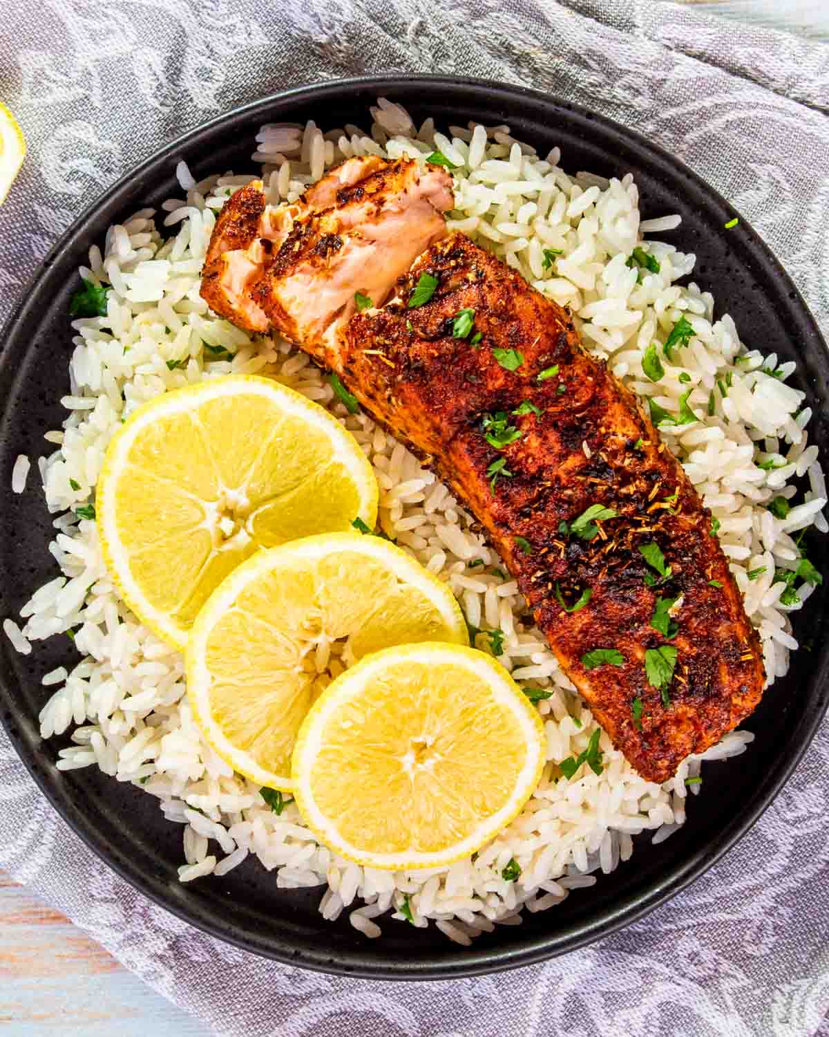 a salmon fillet on a bed of rice with lemon slices.