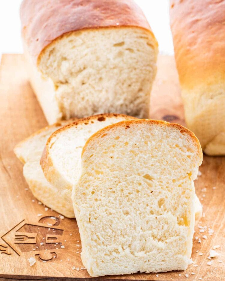 closeup shot of a few slices of bread on a cutting board with the rest of the loaves in the background