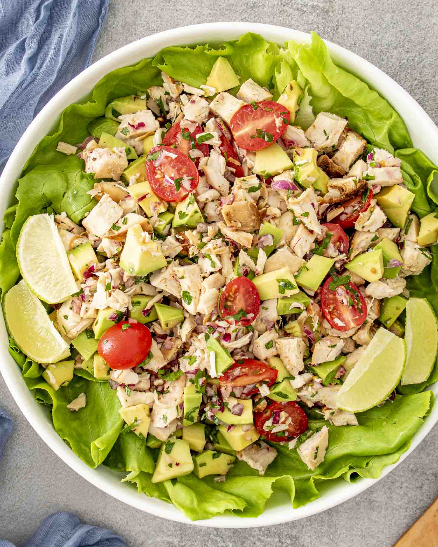 freshly made avocado chicken salad in a large white bowl on top of a bed of lettuce.