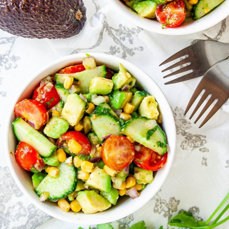 overhead shot of avocado tomato salad in a white bowl.