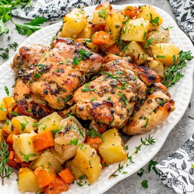 baked honey mustard chicken with potatoes on a white serving platter.