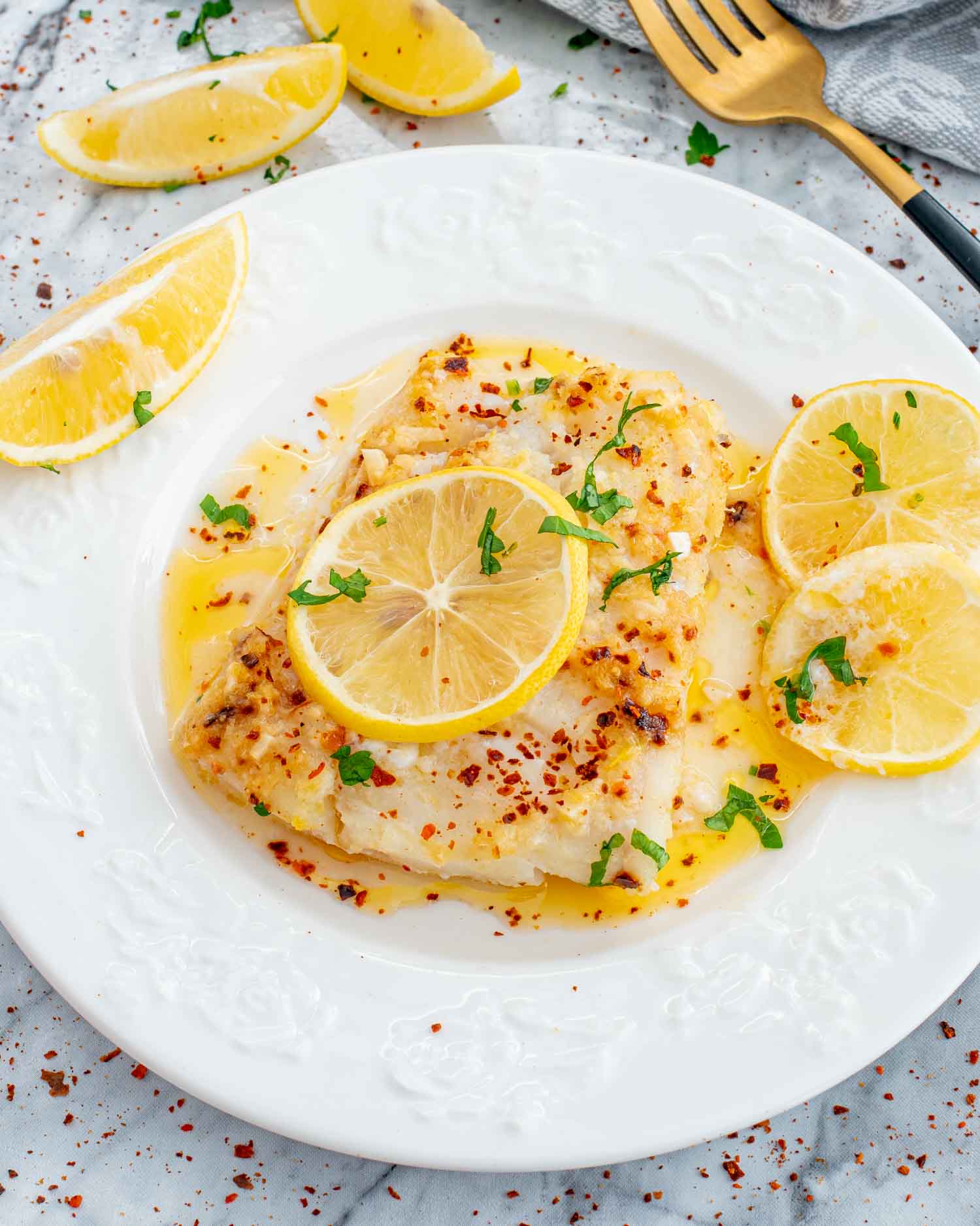 a serving of baked lemon butter cod on a white plate.