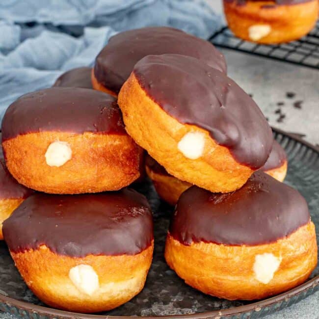 a bunch of boston cream donuts on a serving plate.