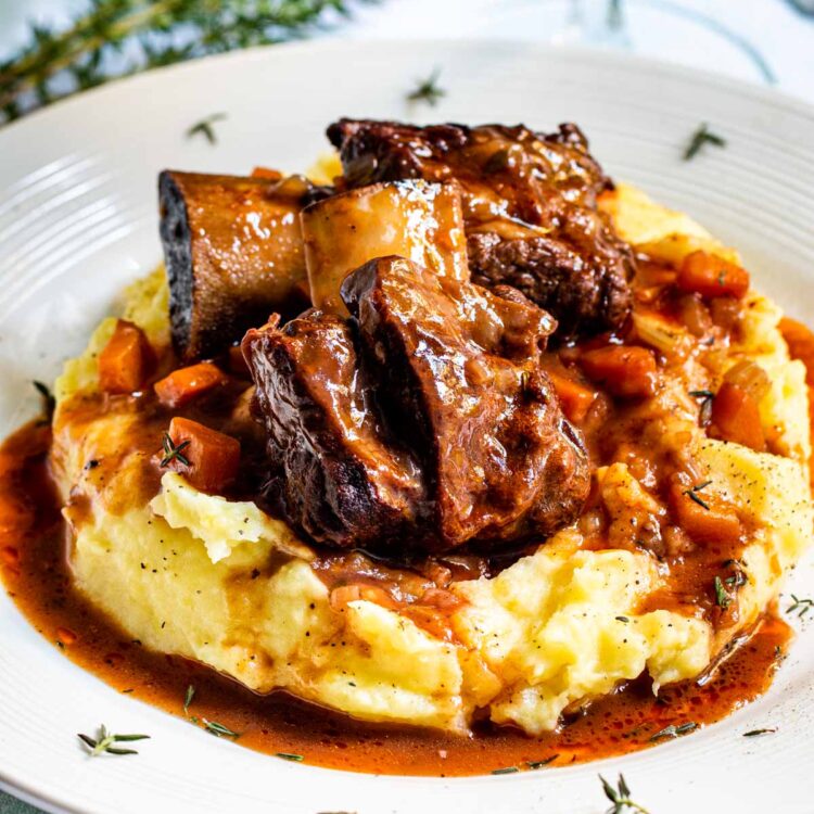 2 beef short ribs on a bed of mashed potatoes.