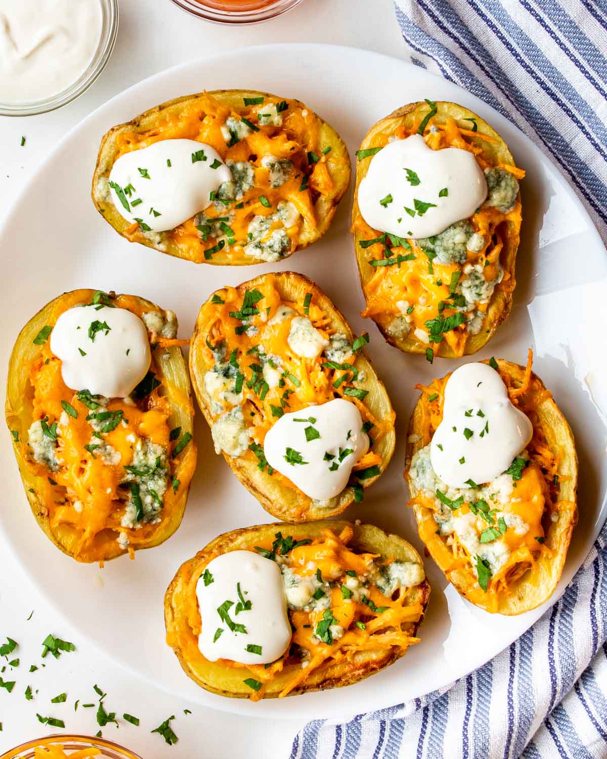 a white plate loaded with buffalo chicken potato skins.