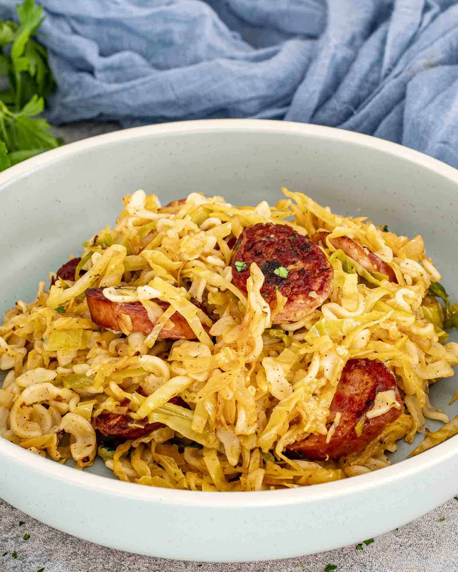 a serving of cabbage and noodles with sausage in a plate.