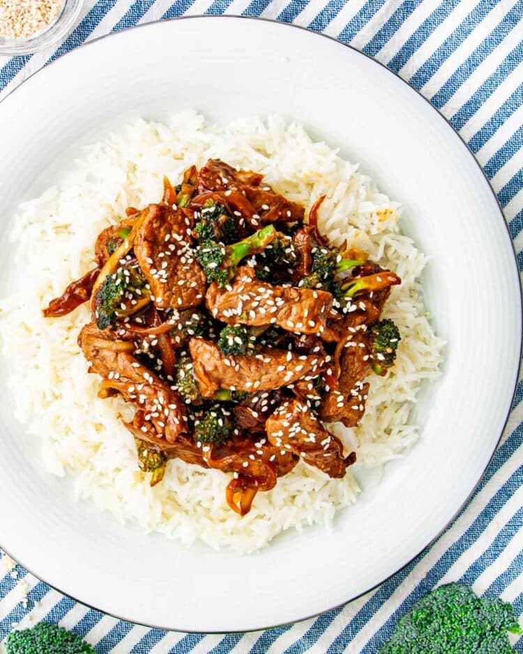 overhead shot of beef and broccoli over a bed of rice garnished with sesame seeds