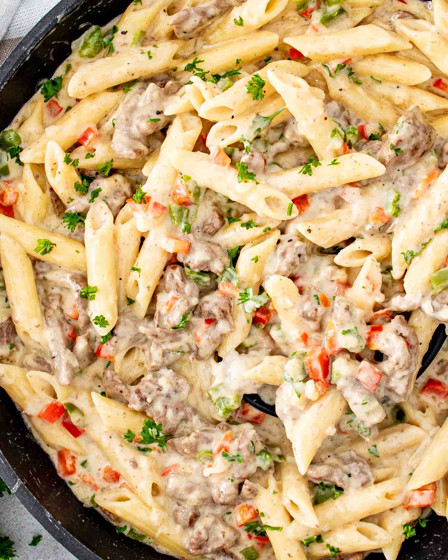creamy cheesy cheesesteak pasta in a skillet.