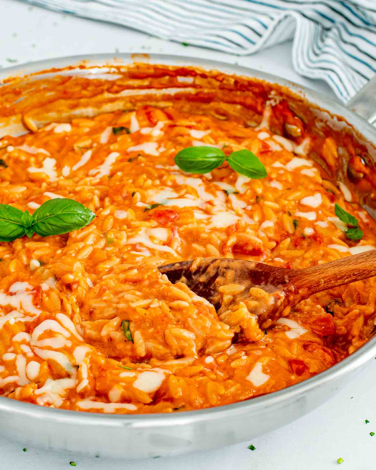 freshly made cheesy tomato basil orzo in a stainless steel skillet.