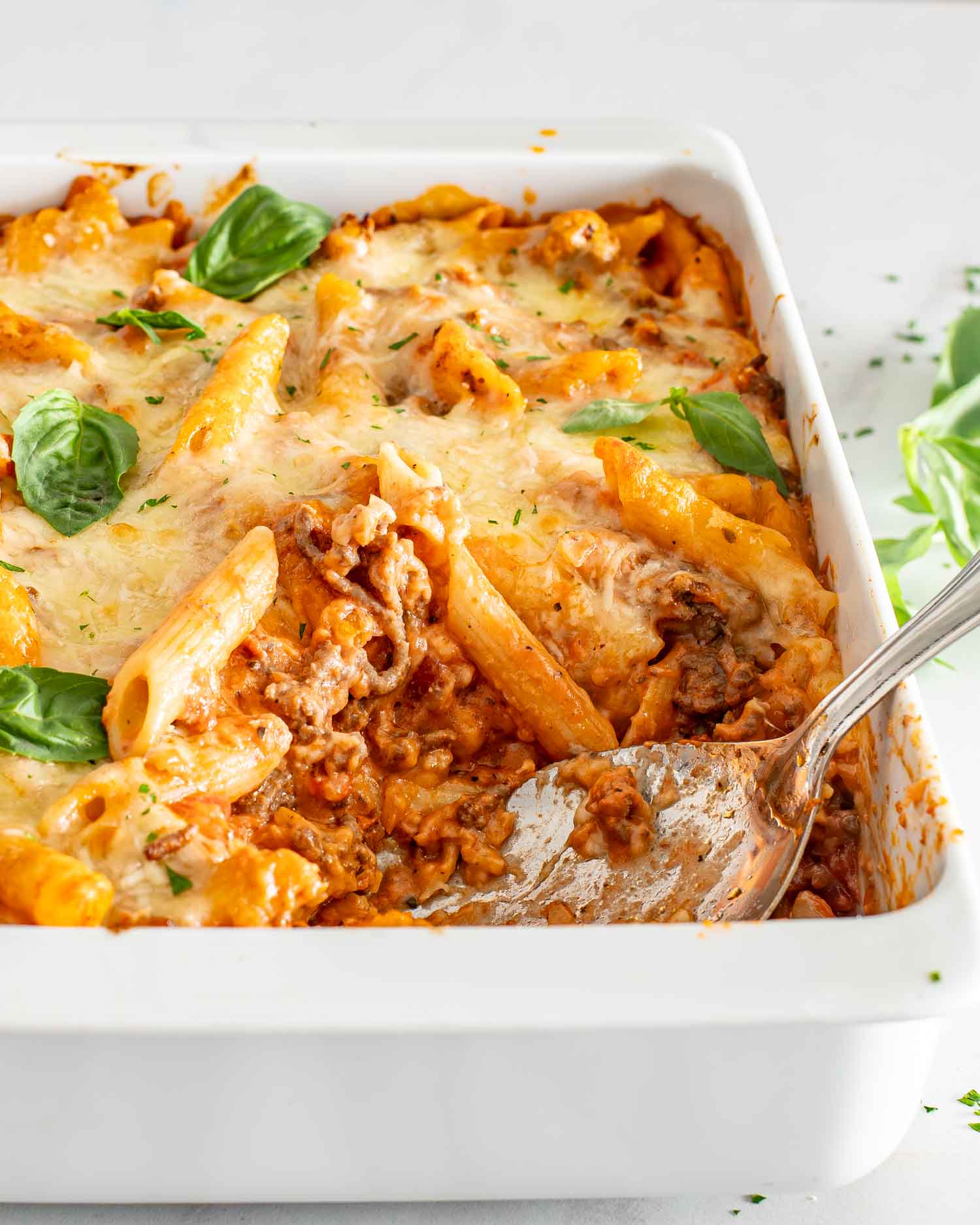 cheesy tomato beef bake in a white casserole dish.
