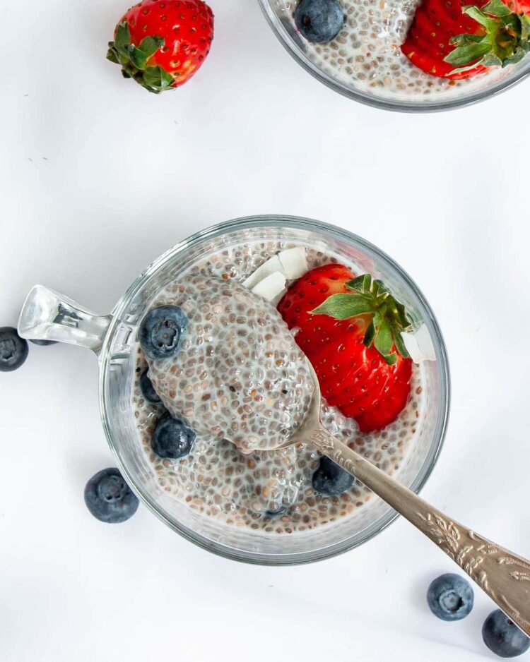 overhead shot of chia pudding in a cup topped with strawberries and blueberries