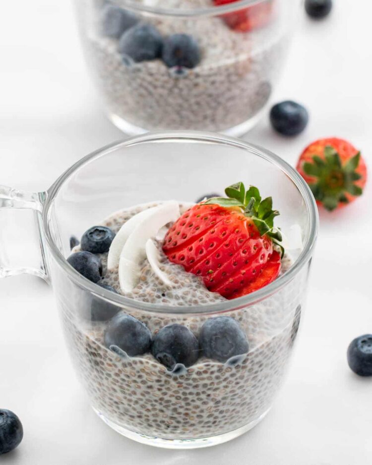 a cup with chia pudding topped with strawberries and blueberries