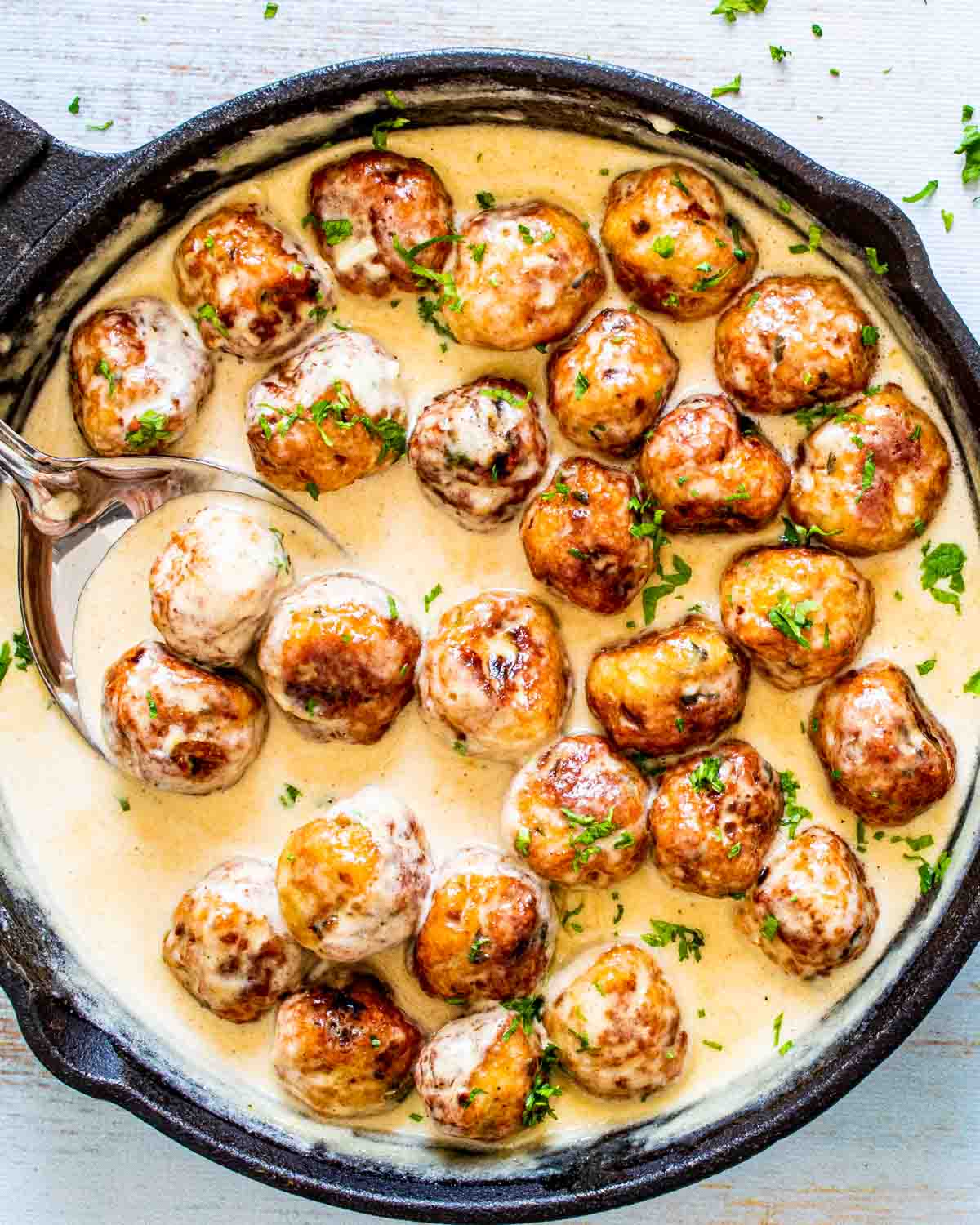 chicken meatballs in alfredo sauce in a skillet.