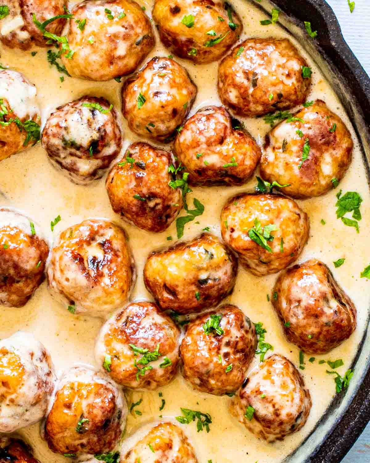 chicken meatballs in alfredo sauce in a skillet.
