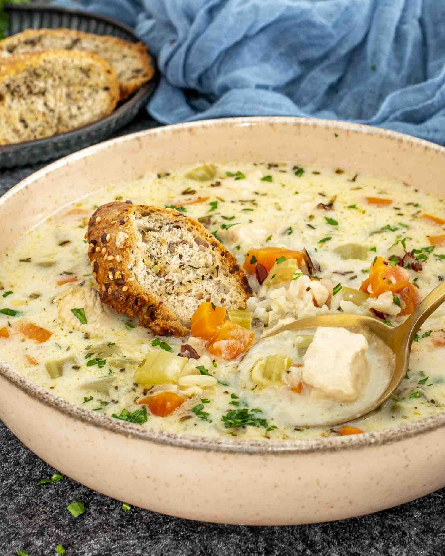 A warm, comforting bowl of creamy chicken wild rice soup, filled with tender chunks of chicken, diced carrots, celery, and wild rice in a rich, herb-infused broth.
