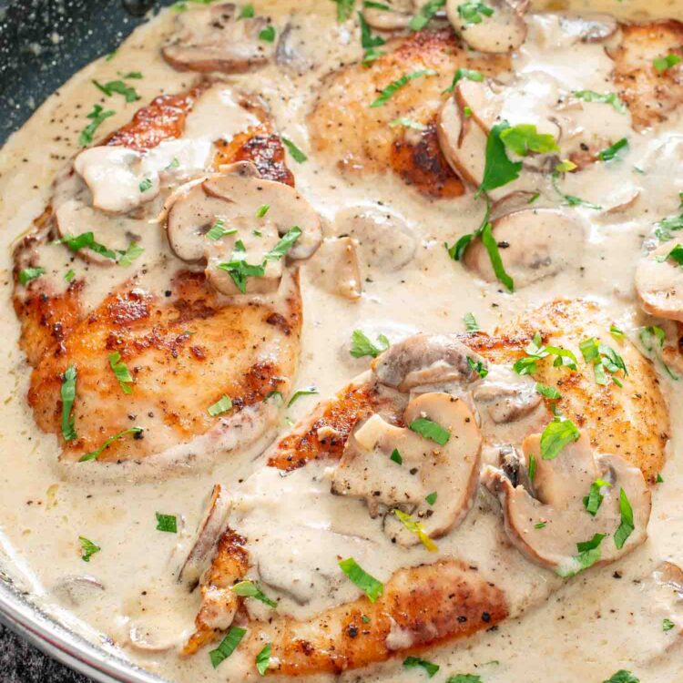 freshly made creamy garlic mushroom chicken in a skillet garnished with parsley.