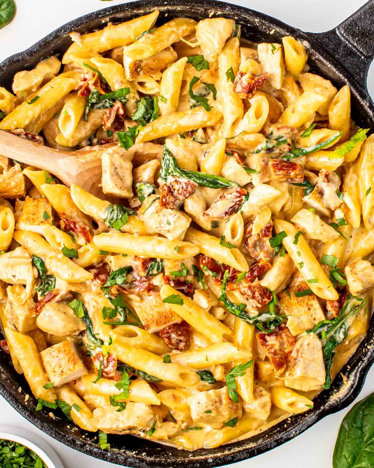 creamy tuscan chicken pasta in a black skillet.