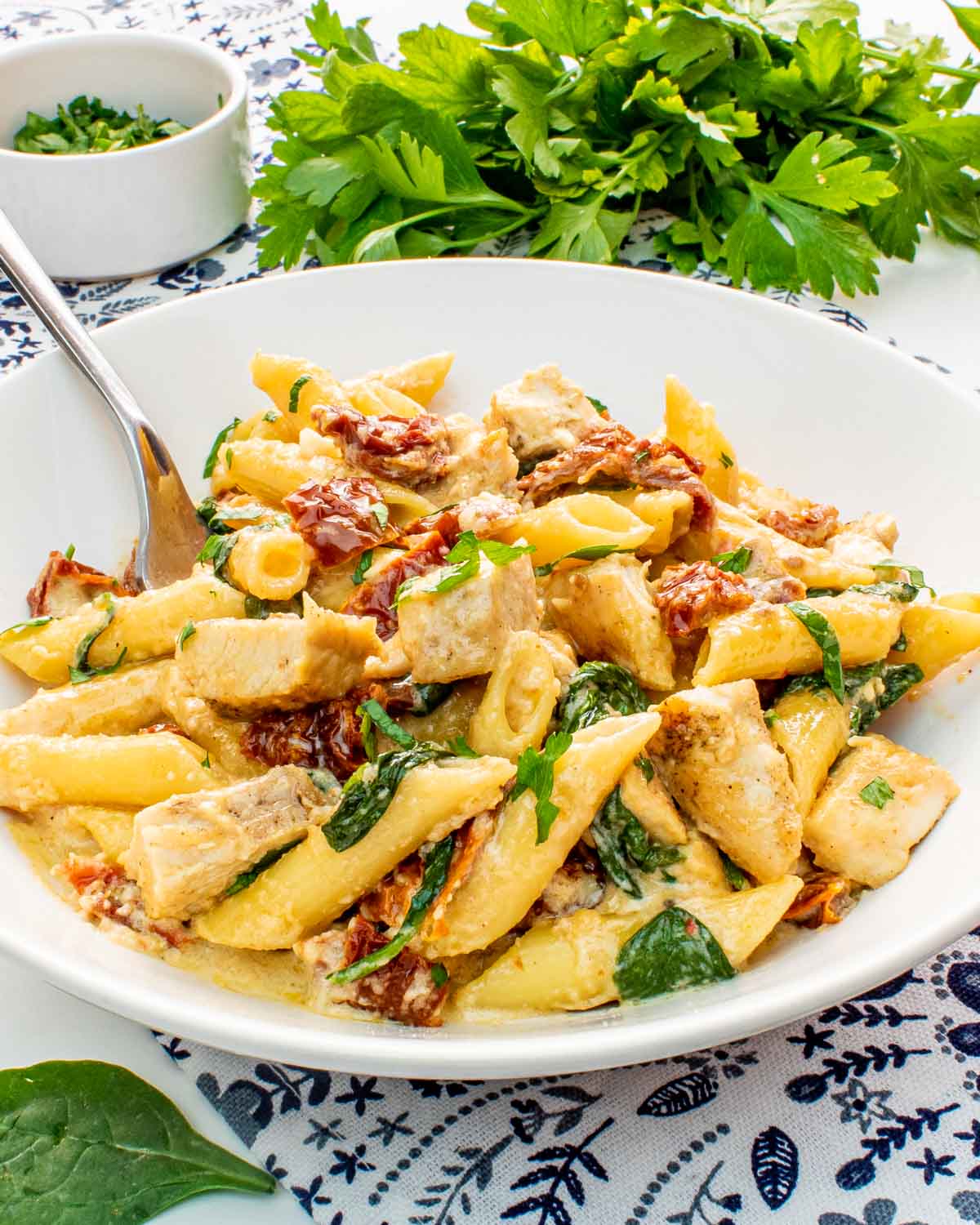 creamy tuscan chicken pasta in a white bowl.