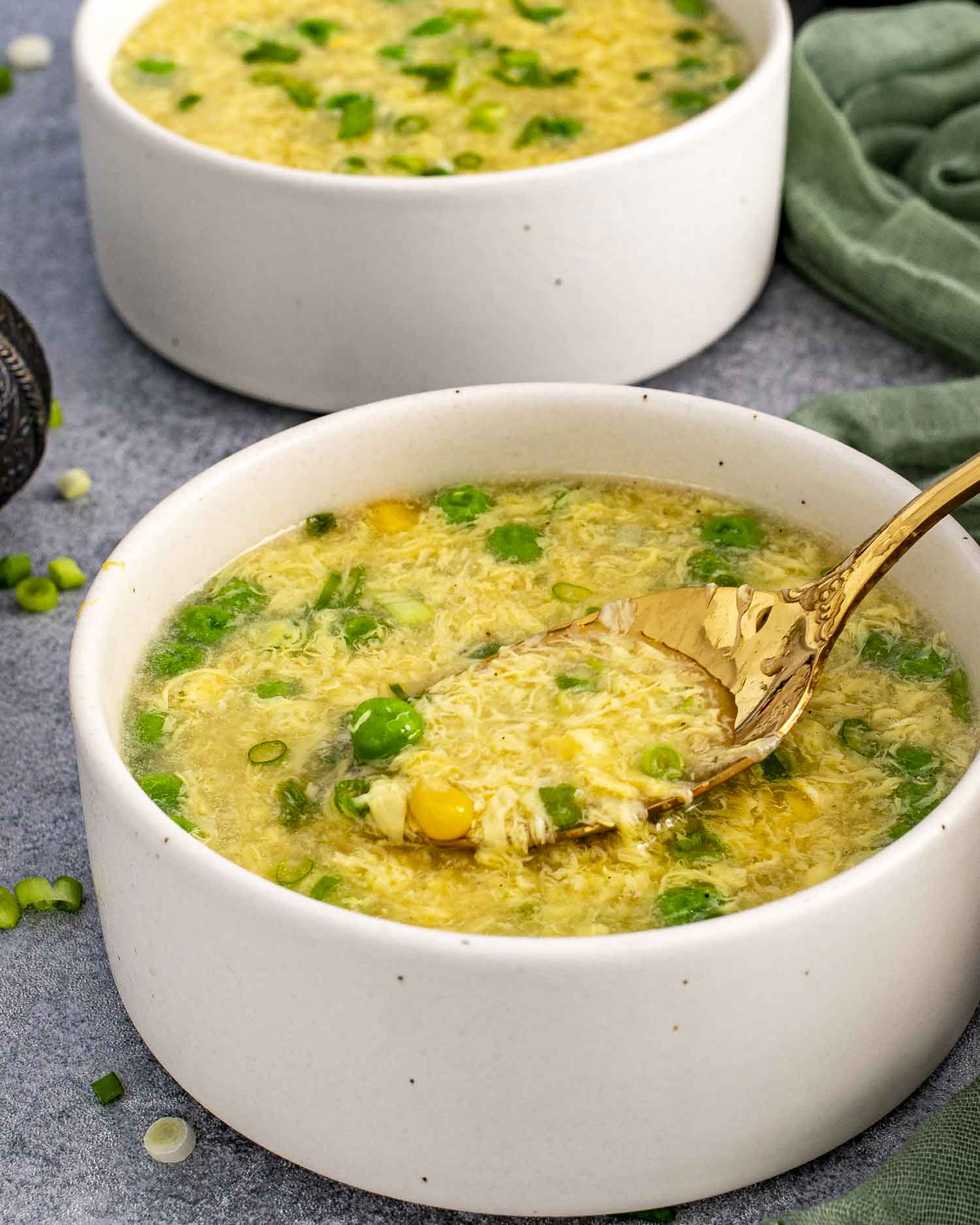 a bowl of freshly made egg drop soup with a spoon inside.