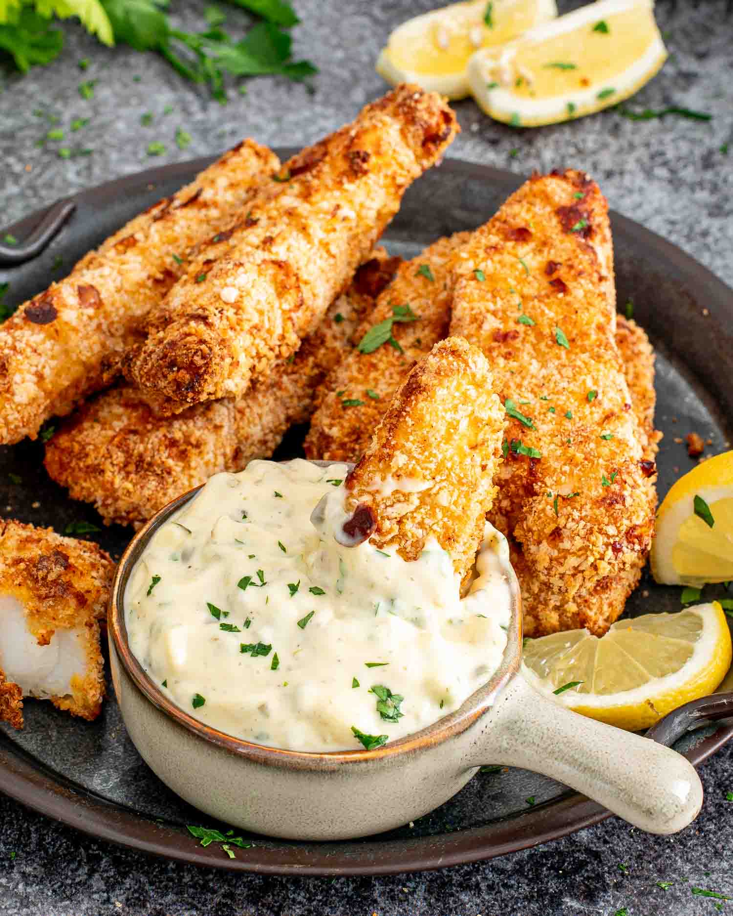 air fried fish sticks on a platter with a bowl with tartar sauce in it.