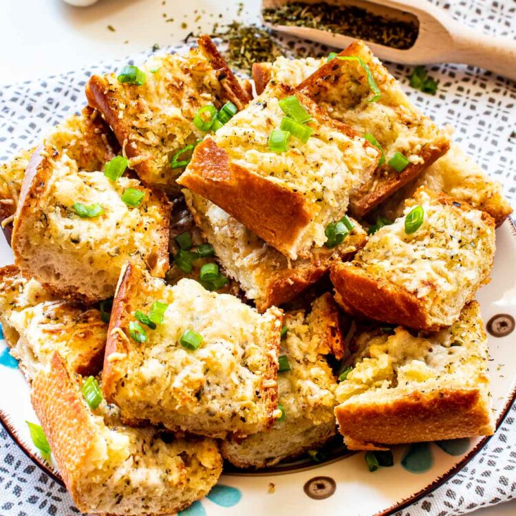 garlic bread cut up in slices on a plate garnished with green onions.