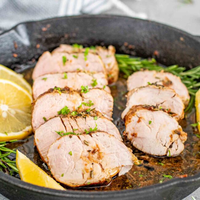 sliced up garlic butter pork tenderloin in a cast iron skillet.
