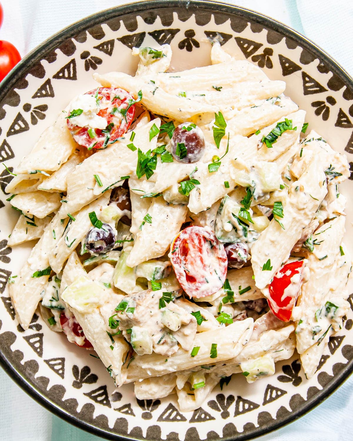 greek chicken pasta on a white and black plate