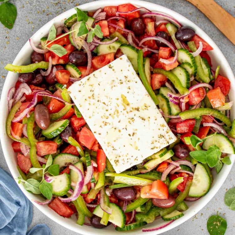 fresh greek salad in a big white serving bowl.