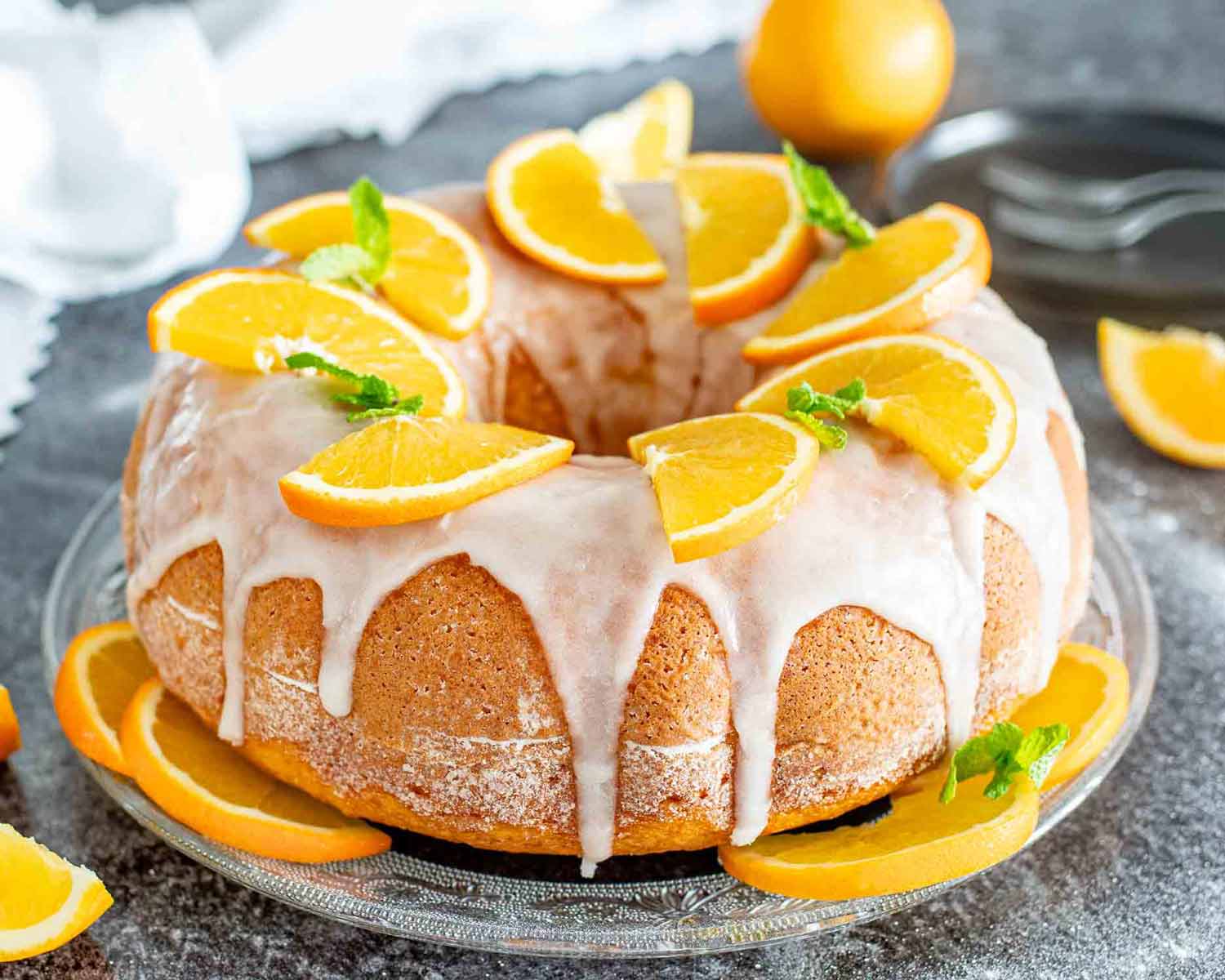 a freshly baked harvey wallbanger cake garnished with orange slices on a cake platter.
