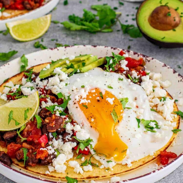 a gorgeous plate of huevos rancheros garnished with queso fresco, sliced avocado and lime wedges.
