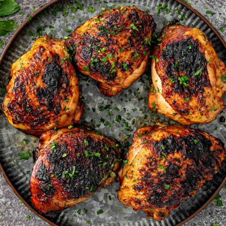 huli huli chicken thighs on a platter garnished with a bit of parsley.