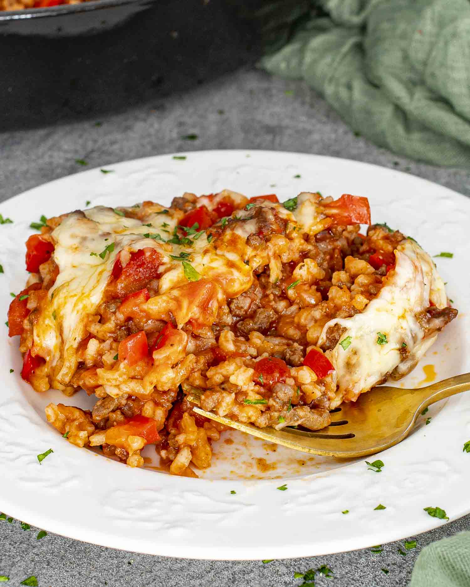 a serving of stuffed pepper casserole on a white plate garnished with a bit of parsley.