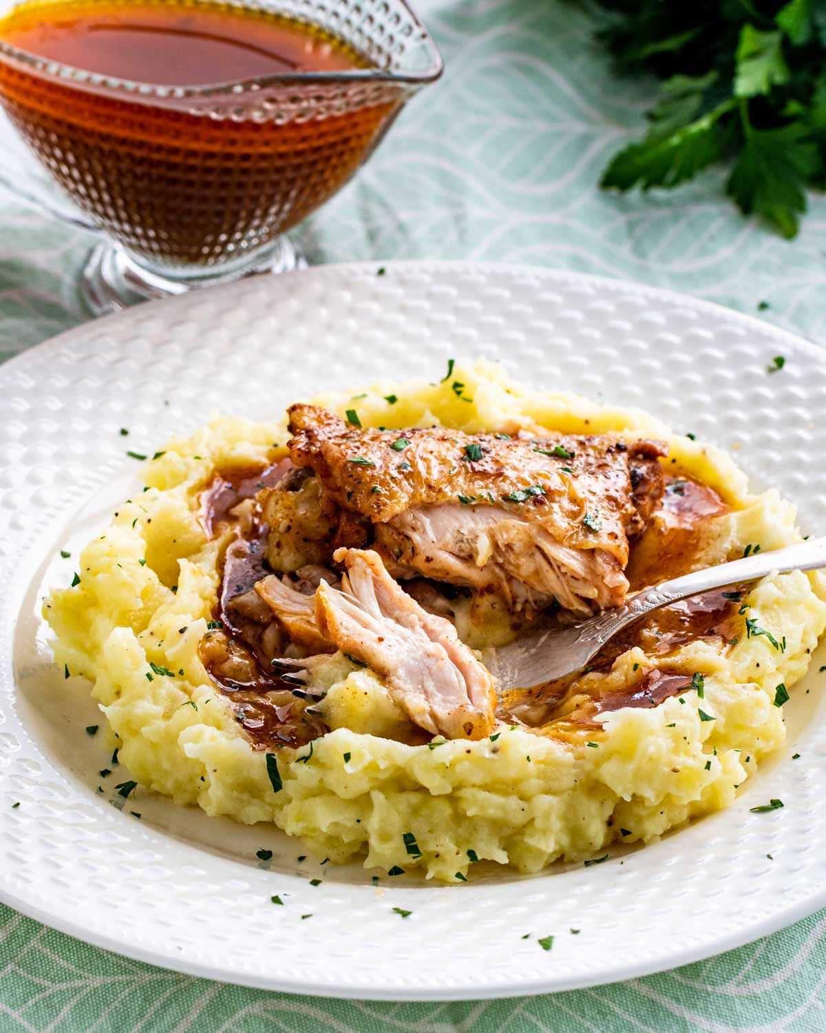 chicken thigh with gravy on a bed of mashed potatoes.