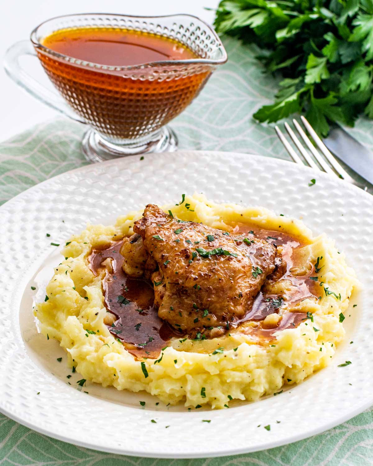 chicken thigh with gravy on a bed of mashed potatoes.