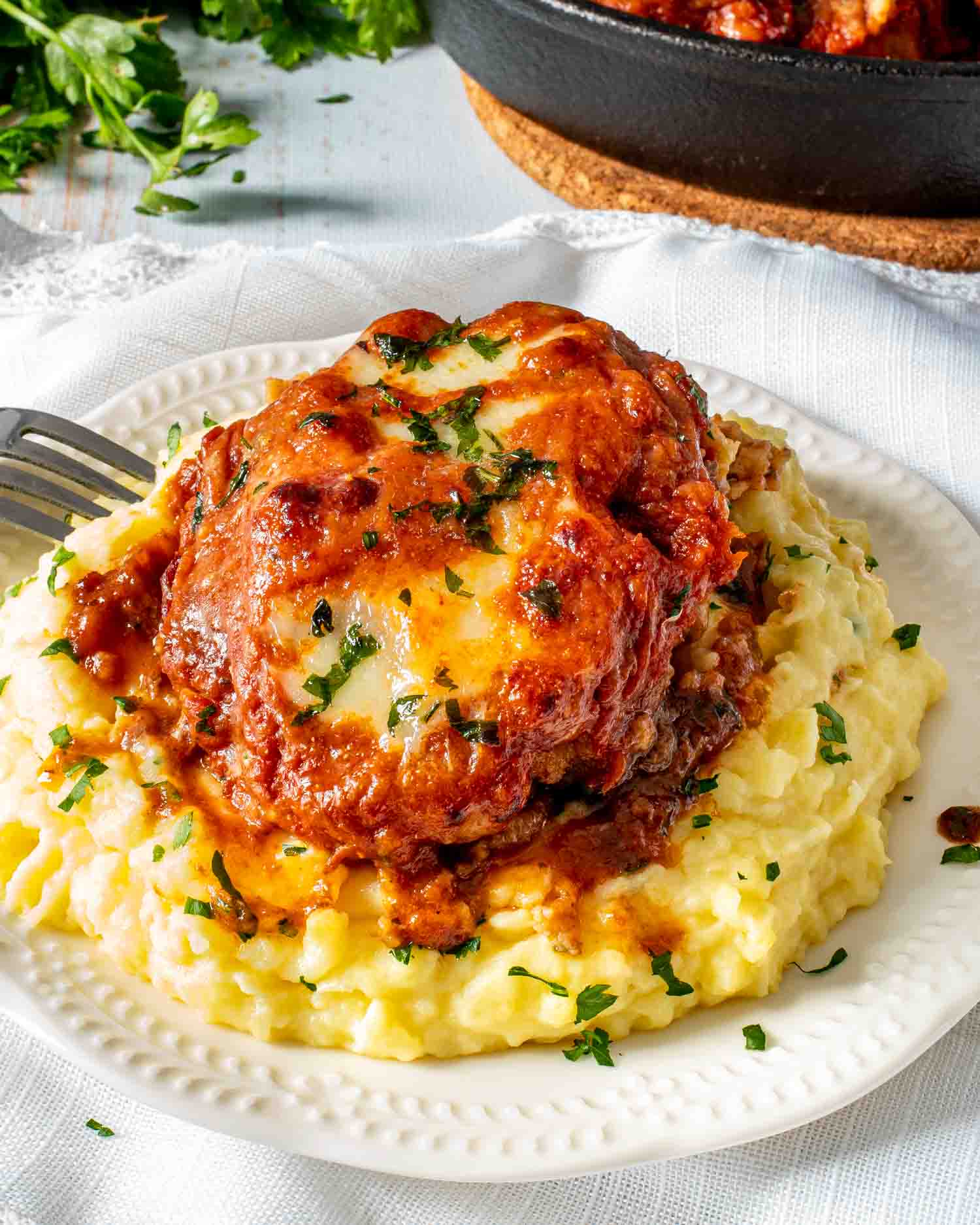 italian hamburger steak over a bed of mashed potatoes.