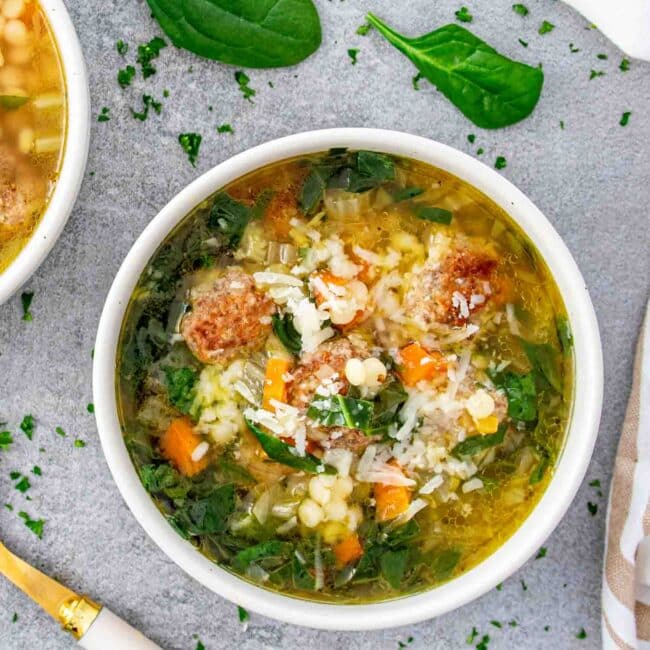a serving of italian wedding soup in a white bowl.