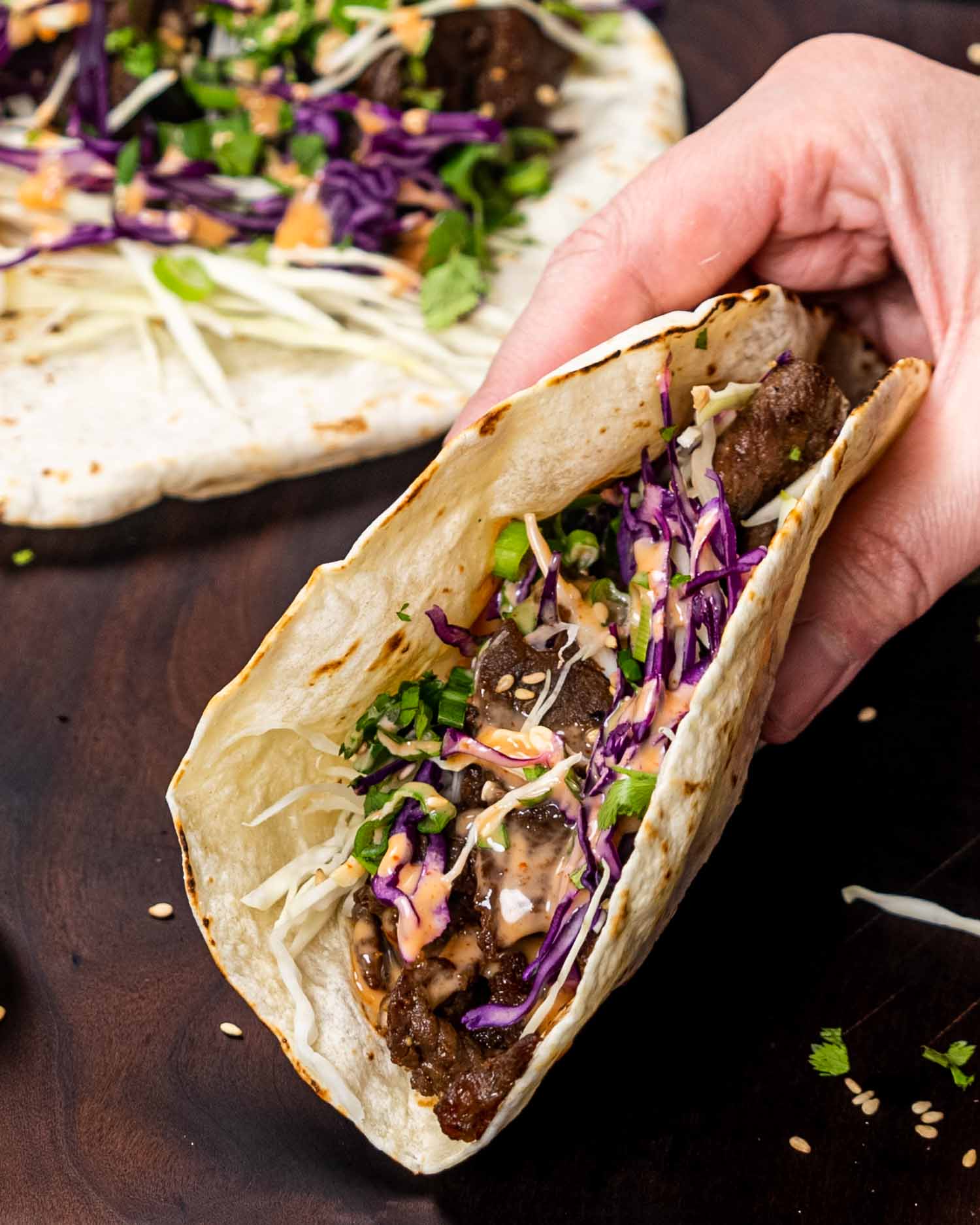 a hand holding a korean beef taco.
