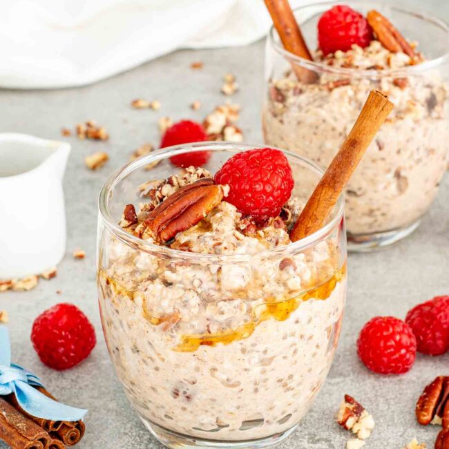 two glasses with maple pecan overnight oats drizzled with maple syrup.
