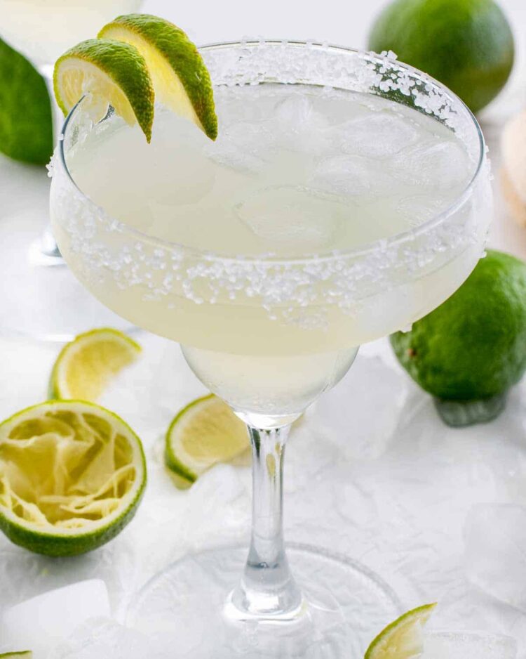 margarita in a rimmed glass with ice and lime wedges