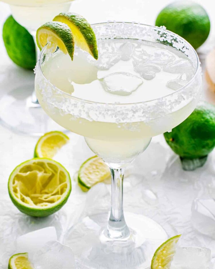 margarita in a rimmed glass with ice and lime wedges