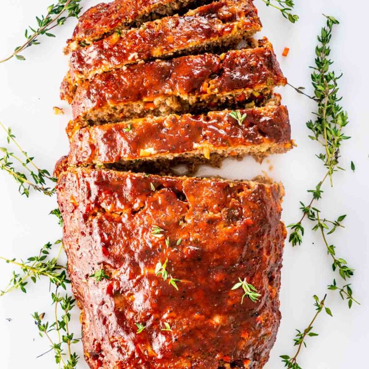 overhead shot of a meatloaf sliced on a white cutting board.