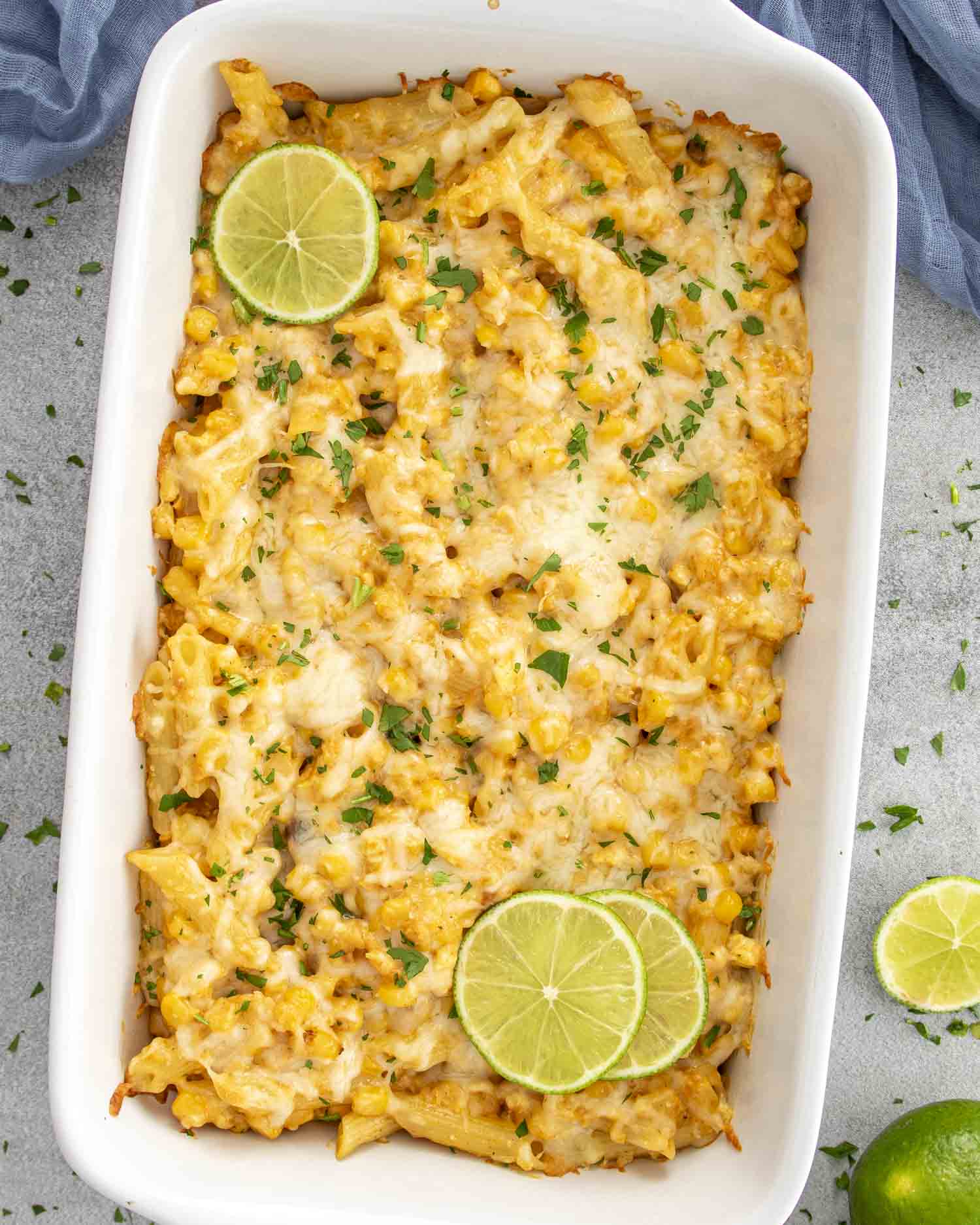 cheesy Mexican Street Corn Pasta Bake in a white casserole dish, garnished with fresh lime slices.