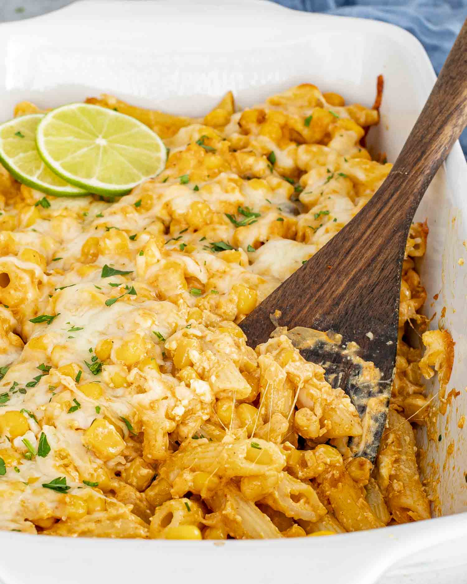 cheesy Mexican Street Corn Pasta Bake in a white casserole dish, garnished with fresh lime slices.