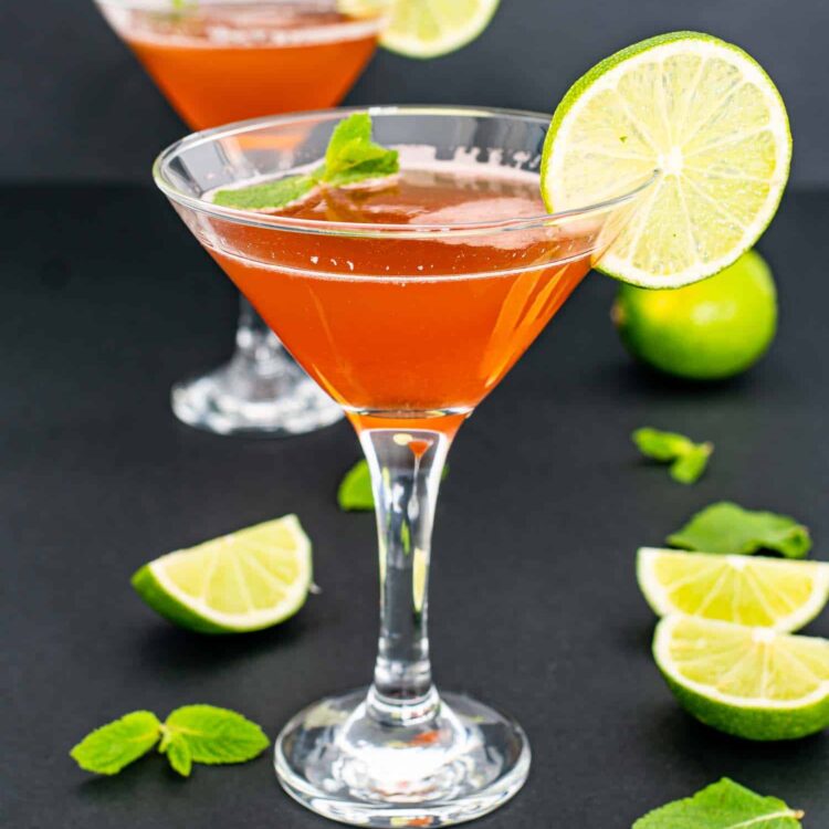 an old cuban cocktail in a glass garnished with lime slice and mint.