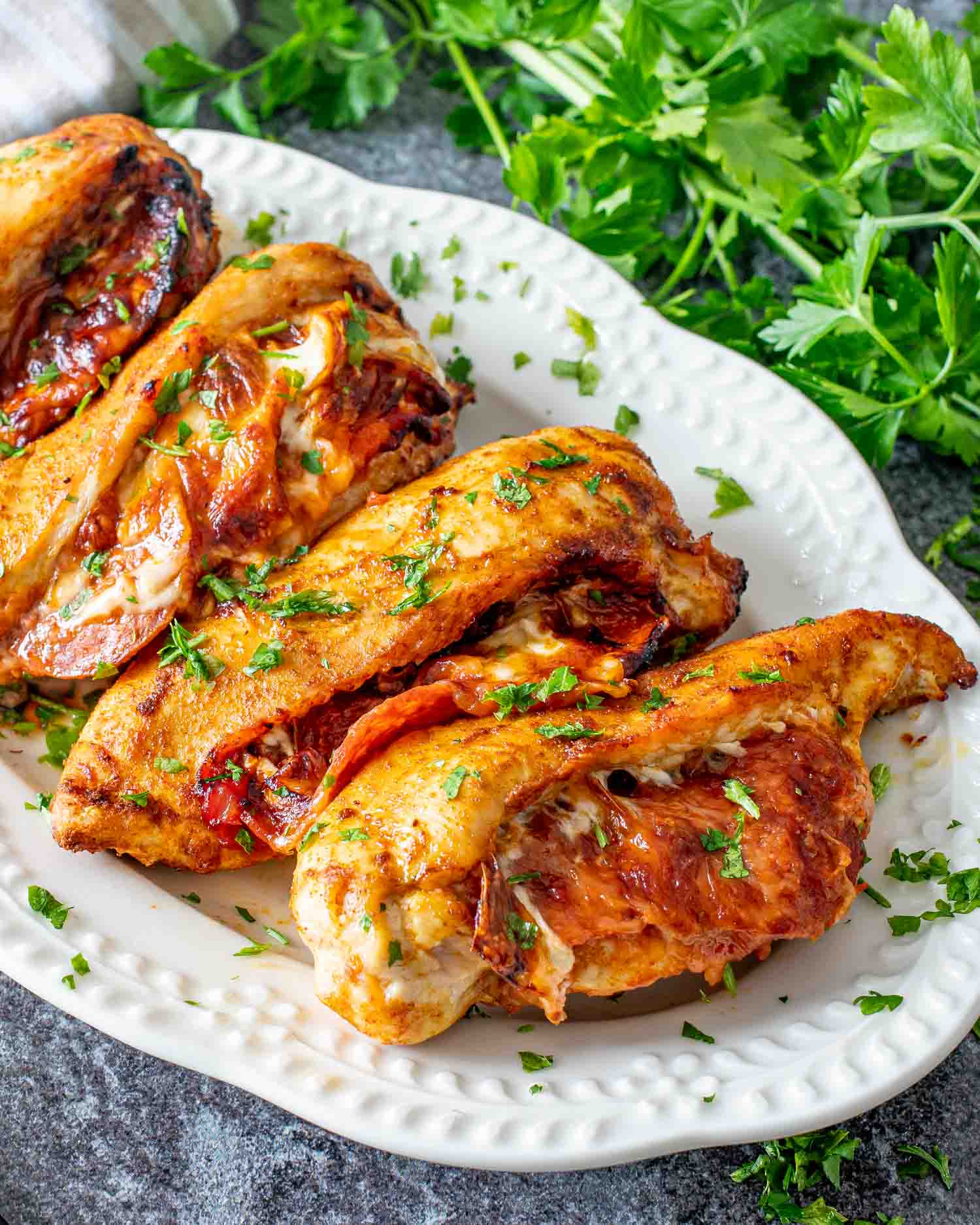 pizza stuffed chicken breasts on a white serving platter.