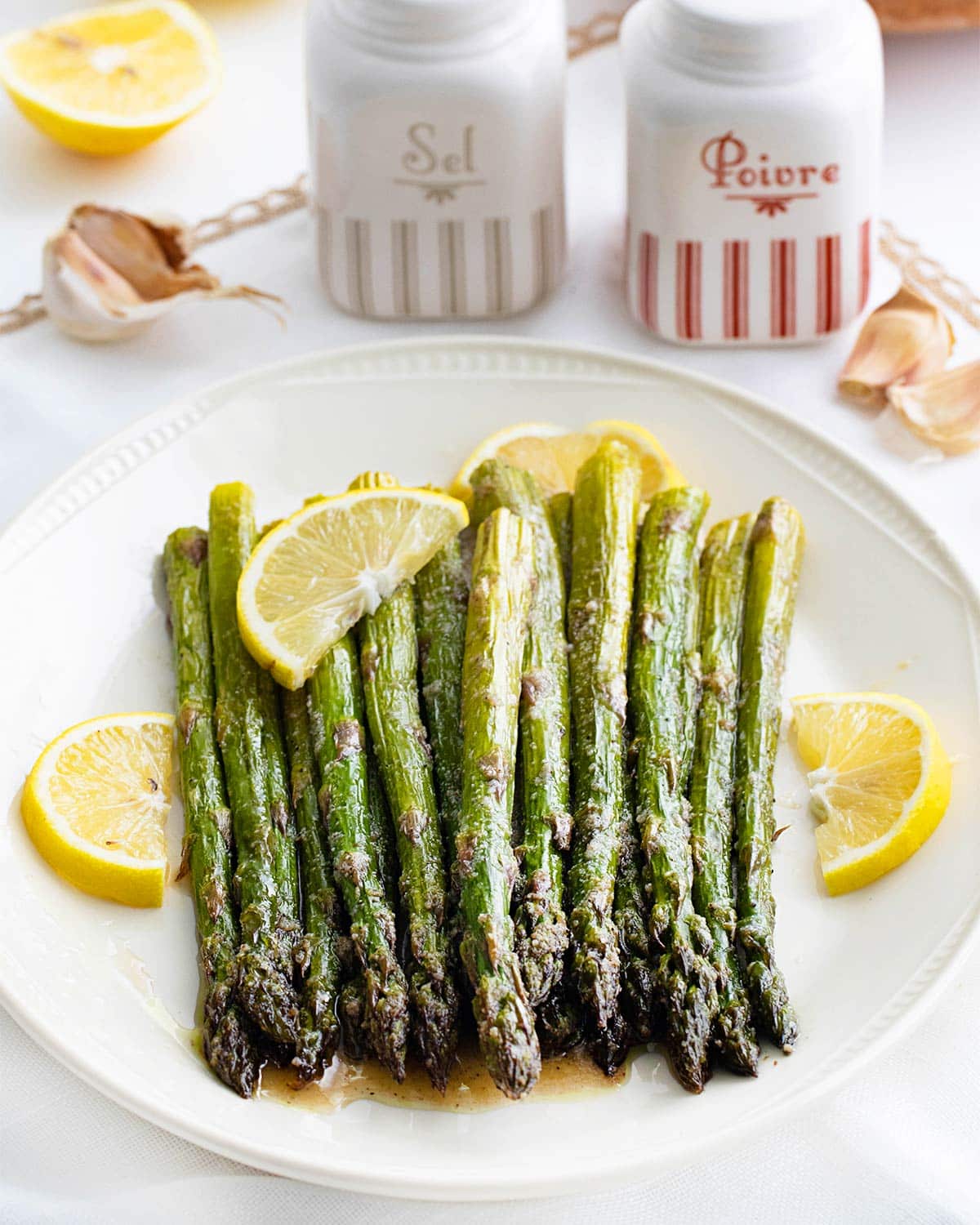 closeup of roasted asparagus on a plate with lemon wedge.