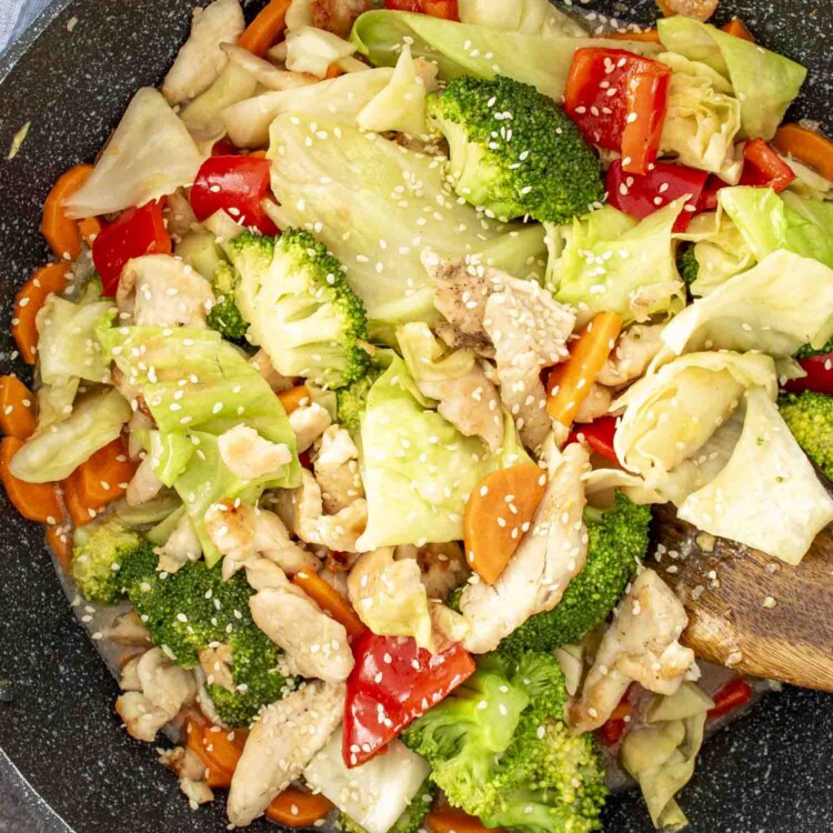 stir fried chicken and veggies in white sauce in a wok, freshly made.