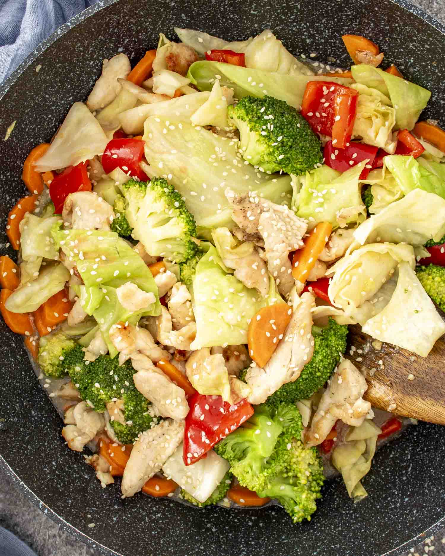 stir fried chicken and veggies in white sauce in a wok, freshly made.