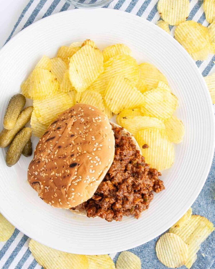 overhead shot of sloppy joe sandwich with chips on a plate