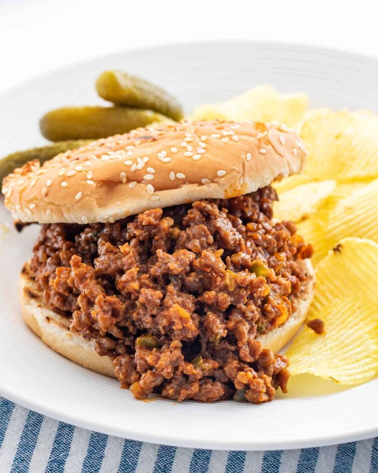 a sloppy joe on a white plate with a side of chips